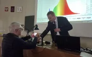 Uczestnik wykładu przygotowujący smartfon do pomiaru rozkładu widmowego promieniowania emitowanego przez ekran urządzenia mobilnego podczas części eksperymentalnej prowadzonej przez Przemysława Tabakę.
